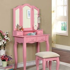 a pink dressing table with mirror and stool