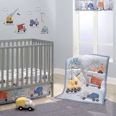 a baby crib bedding set with construction vehicles on it and a toy truck