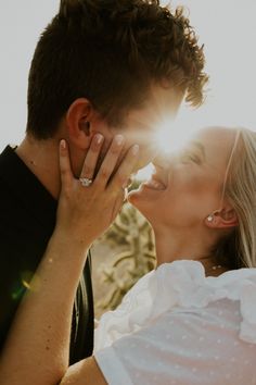 a man and woman kissing each other in front of the sun with their faces close together