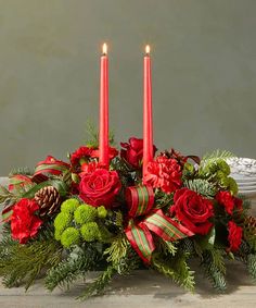 a centerpiece with red roses, greenery and candles