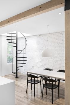 a dining room table with chairs and a spiral staircase