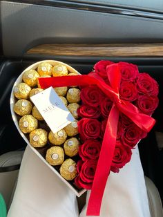 a heart shaped box filled with chocolates and roses in the back seat of a car