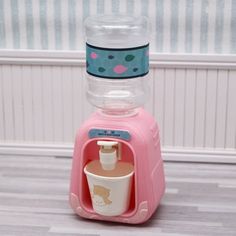 a pink toy machine with a cup in it