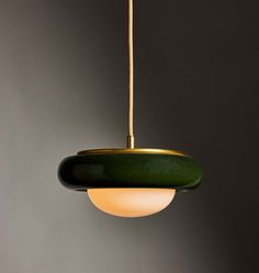 a green and gold pendant light hanging from a ceiling fixture in a room with grey walls