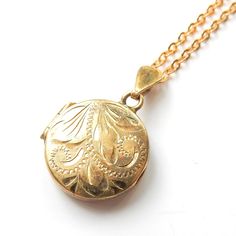 A petite rolled gold locket. This sweet circle shaped locket has an eye catching hand engraved motif.   This locket would be perfect for storing a small photograph of a loved one inside. A wonderful piece of vintage keepsake jewellery! This locket comes presented in a Milly's Marvel's gift box hand tied with ribbon. All other boxes are for display purpose only. DIMENSIONS LOCKET - 1.4cms x 1.4cms LENGTH OF CHAIN - 16inches ERA - Circa 1960s WEIGHT - 3.4grams HALLMARKS - "25 Micron Rolled Gold" t Gold Locket Necklace With Vintage Charm, Gold Pendant Locket Necklace With Vintage Charm, Gold Etched Round Disc Jewelry, Vintage Circle Necklace For Gifting, Vintage Circle Necklace For Gifts, Dainty Engraved Pendant Locket Necklace, Dainty Locket Necklace With Round Pendant, Gold Heirloom Brass Locket Necklace, Heirloom Gold Brass Locket Necklace