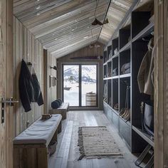 a room with wooden walls and shelves filled with coats, shoes and blankets on the floor