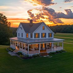 a large white house sitting on top of a lush green grass covered field under a cloudy sky