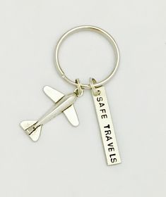 a silver keychain with a plane on it that says see travels and is hanging from the side