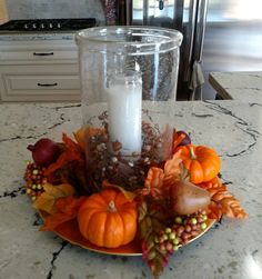 a candle is lit on a plate with autumn decorations