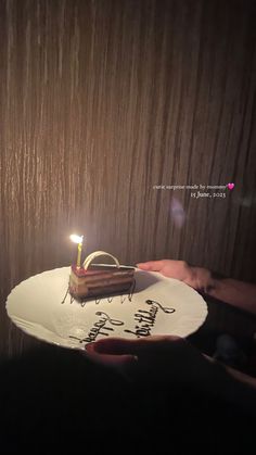 a piece of chocolate cake on a white plate with a lit candle in the middle