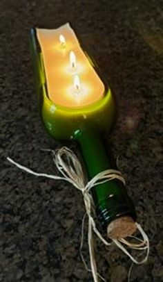 a green bottle with a lit candle in it sitting on the ground next to a string