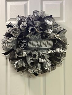 a wreath is hanging on the front door with an oakland football team name and ribbon