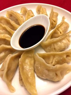 dumplings with dipping sauce on a white plate