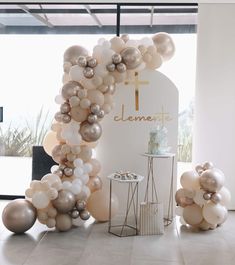 an arch made out of balloons with a cake on the table in front of it