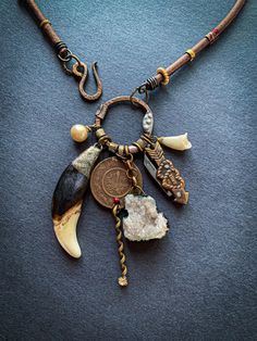 Long cluster necklace with  - Vintage glass pearl  - Fang bailed with epoxy and metal leaf. This is actually a bovine bone shaped into a fang.  - Kuchi tribal coin charm with curly rhinestone charm - Geode chunk bailed with epoxy and metal leaf  - Mini folding knife with hearts - Cold porcelain lily - Hammered and soldered ring - Thick hammered brass hook - Leather cord - Rings of vintage tin - The necklace measured without the focal is 25.5" in length  - The focal from the top of ring is 3" Unique Vintage Jewelry With Lobster Clasp, Handmade Statement Necklace, Horn Earrings, Brass Hook, Hammered Brass, Cluster Necklace, Metal Leaves, Cluster Pendant, Cold Porcelain