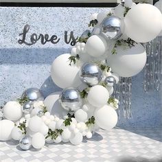 white balloons and greenery are arranged in front of a love us sign