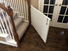 an open door leading to a set of stairs in a house with wood floors and white railings