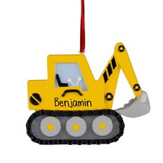 a yellow construction vehicle ornament hanging from a red ribbon on a white background