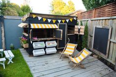 an outdoor kitchen made out of pallets with yellow and white striped awnings