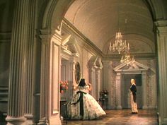 a man and woman standing in an ornate hallway