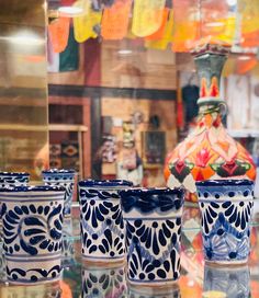 four blue and white cups sitting on top of a glass table in front of a store window