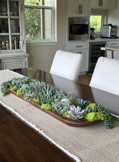 a wooden tray with succulents on top of a table in a kitchen