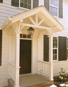 a white house with black shutters and a lantern on the front porch