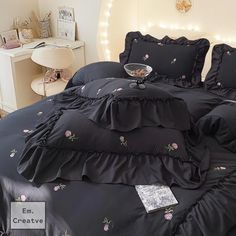 a bed with black ruffled sheets and pink flowers on the comforter is shown