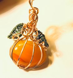 "Pumpkin pendant copper wire wrapped oval orange agate gemstone cabochon.  There's curly vines and Leaves wrapped with green wire.  It has a bail at the top for any desired chain you have to go through.   Chain shown not included. It measures about 1\" wide and 1.5\" high including bail." Orange Wire Wrapped Handmade Jewelry, Orange Copper Wire Wrapped Jewelry, Orange Copper Wire Jewelry As A Gift, Orange Copper Wire Jewelry For Gifts, Unique Orange Wire Wrapped Jewelry, Orange Carnelian Wire-wrapped Jewelry, Stone Pumpkin, Orange Agate, Wire Weaving