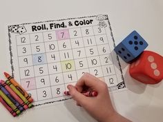 a child is playing with a roll and find color game on the table next to some crayons