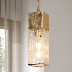 a light fixture hanging from the ceiling in a room with white walls and window curtains