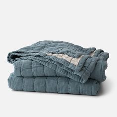 two blankets are folded on top of each other, one is blue and the other is grey