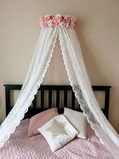 a bed with a white canopy over it and pink sheets on top of the bed