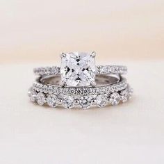 an engagement ring set with a cushion cut diamond in the center and side stones on each band