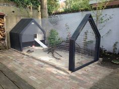 an outdoor area with two small houses made out of metal wire and brick pavers