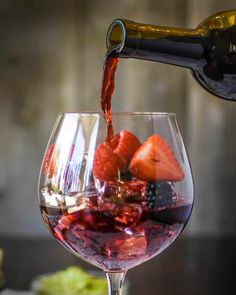 wine being poured into a glass filled with fruit