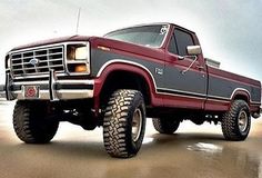 a red and gray truck parked on top of a sandy beach