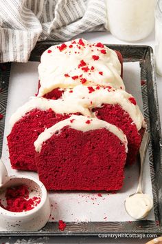 a red velvet cake with white frosting and sprinkles on a tray