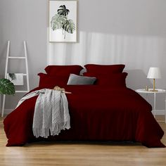 a bed with red sheets and pillows in a room