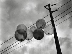 black and white photograph of street lights with cloudy sky in the backgrouund