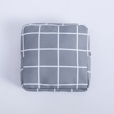 a gray and white checkered pillow on a white surface with a small zippered pocket