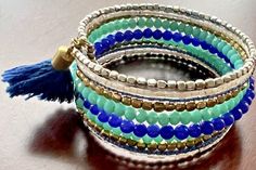 Elevate your wrist game with this stunning Aqua Blue Silver Tone Stack Wide Bracelet. The bohemian beaded bracelet features an open cuff design with a braided chain type. The beautiful blue color of the beads adds a touch of retro beauty to your outfit. Crafted from quality glass material and metal alloy, this cuff bracelet is perfect for adding a personalized touch to your jewelry collection. The 2.5-inch item length ensures a comfortable fit for most wrist sizes. The charm type is a bead, maki Bohemian Multi-strand Beaded Bracelets With Silver Beads, Beaded Multi-strand Metal Bracelets, Bohemian Multicolor Wrap Bracelet For Party, Hand Wrapped Blue Beaded Bangle Bracelet, Blue Bracelets With Colorful Beads For Festival, Colorful Beads Wrap Bracelet For Parties, Festival Blue Bracelets With Colorful Beads, Blue Bangle Bracelets For Festival, Bohemian Wrap Bracelet With Colorful Beads For Party