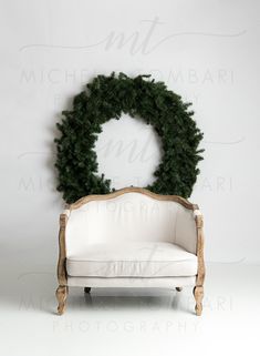 a white chair with a wreath on top of it in front of a white wall