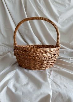 a wicker basket sitting on top of a white sheet