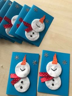 four snowmen made out of felt sitting on top of blue envelopes