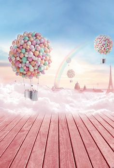 balloons floating in the sky over a wooden floor with clouds and rainbows behind them