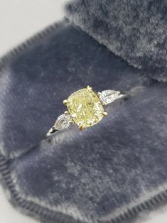 a yellow diamond ring sitting on top of a velvet case