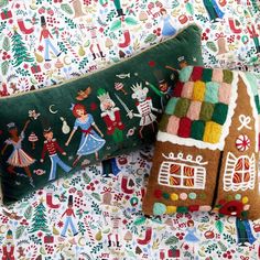 two decorative pillows are sitting on a bed with christmas themed sheets and pillow cases, one has a gingerbread house