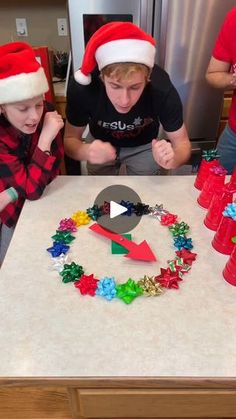 three boys wearing santa hats around a table with christmas decorations on it and cups in front of them