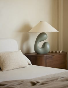 a bed with a lamp on top of it next to a night stand and nightstand